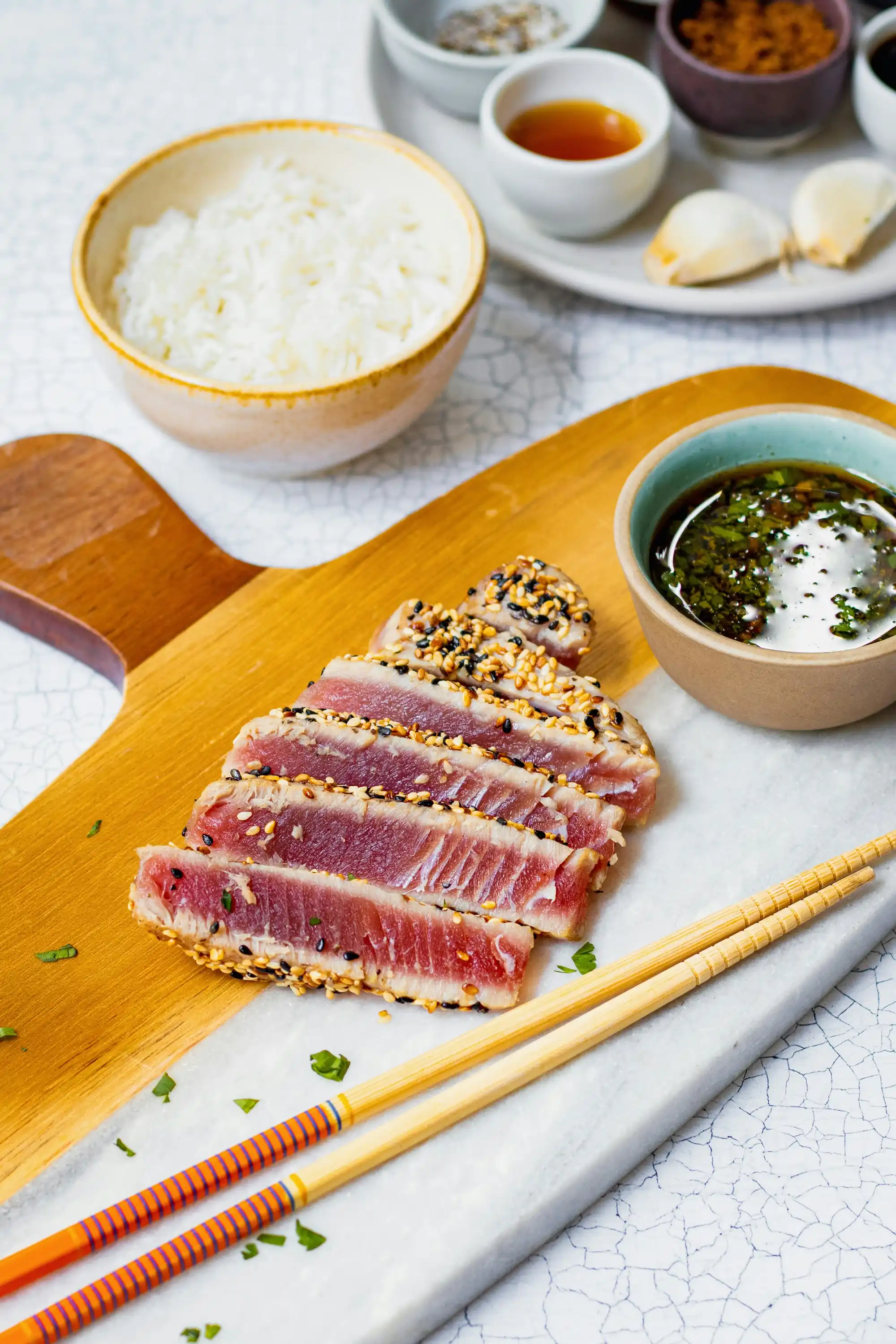 Ястие с порции леко опечено тон, нарязано на ивици и поръсено със сусам, поднесено върху дървена дъска. Отстрани на дъската са поставени две дървени клечки за хранене със синьо-оранжеви орнаменти. В заден план са разположени купички с бял ориз, чили сос, соев сос и чесън, както и малка чиния с дип сос и чаена чашка.