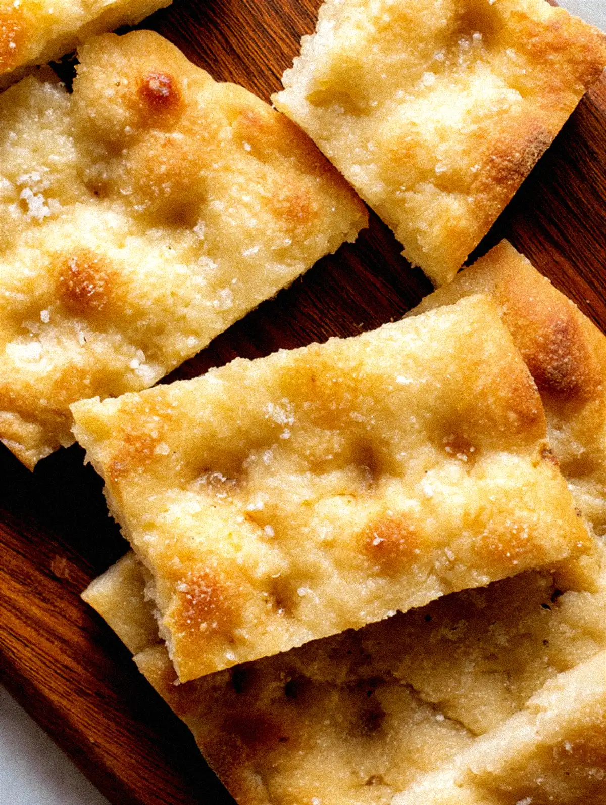 Домашна фокача с розмарин, сервирана с купичка зехтин и розмаринови клонки върху решетка.